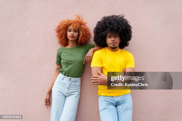 vibrant latin duo: afro hair, colorful attire, urban pose - cabelo volumoso imagens e fotografias de stock