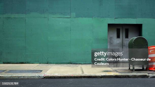 painted and patinated wood panels in green with doors, cement sidewalk with mail box and road in manhattan, new york state, united states - marciapiede foto e immagini stock