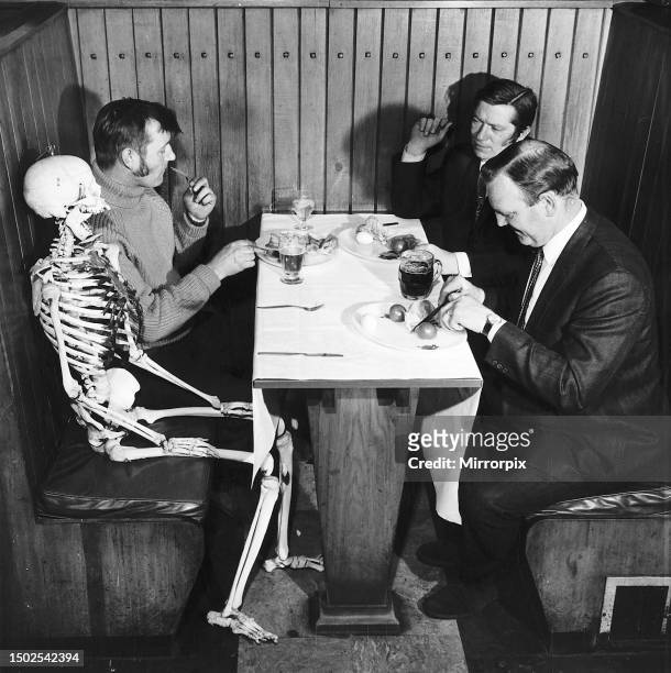 Skeleton sits at pub table waiting to be served. 26th May 1970.