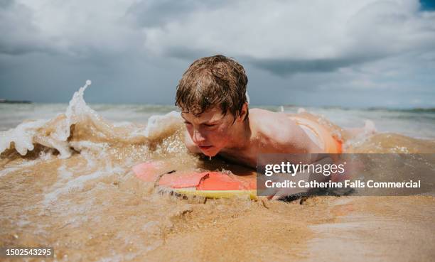 a young teenage boy bodyboards - extreme sports kids stock pictures, royalty-free photos & images