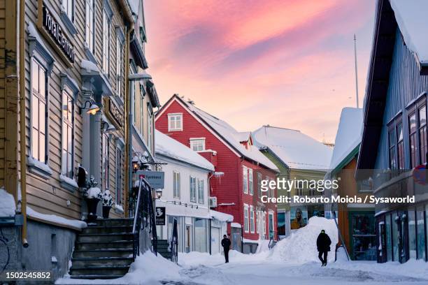 cold sunrise over the snowy multicolored houses - tromsö stock-fotos und bilder