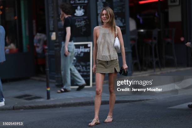 Camille Rowe is seen wearing back-free, sleeveless and shiny top from Ludovic de Saint-Sernin, shiny sandals, a white bag and a short green skirt...