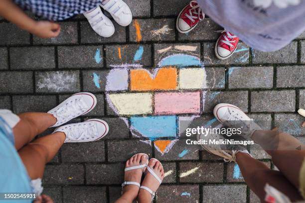 children standing next to a children’s chalk drawing heart shape on the ground - family chalk drawing stock pictures, royalty-free photos & images