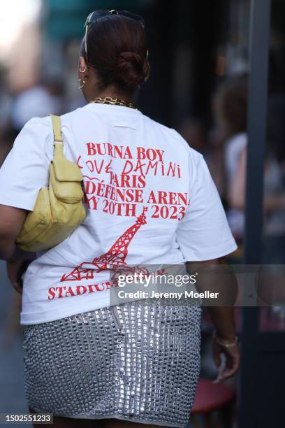 Fashion Show Guest is seen wearing miu miu shades, golden jewelry, a white tshirt with the logo of jean paul gautier, a shiny silver skirt, silver...