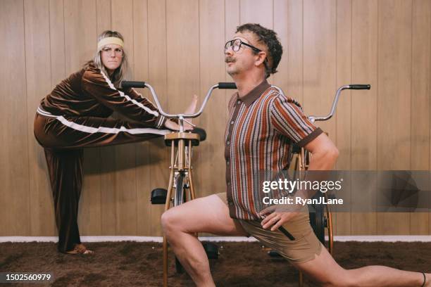 retro nineteen eighties aesthetic exercise bike couple - funky middle age couple stockfoto's en -beelden