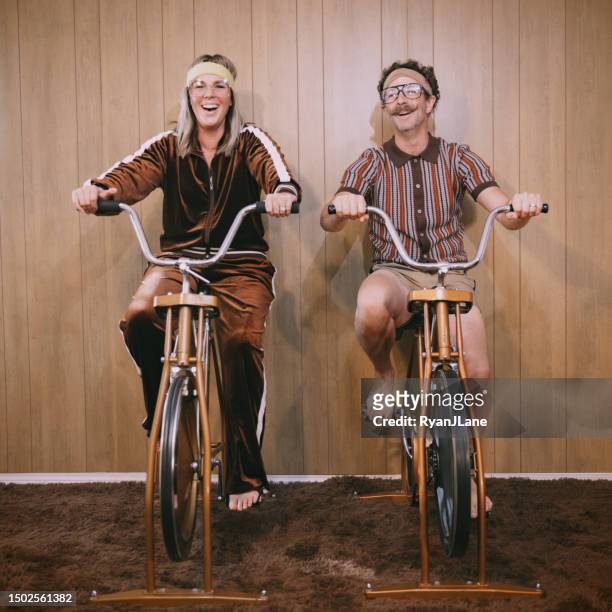 retro nineteen eighties aesthetic exercise bike couple - funky middle age couple stockfoto's en -beelden