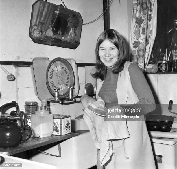 Teenager Jeanette Green doing household chores at her home - here washing up in the kitchen. December 1969.