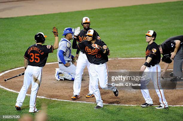 Manny Machado of the Baltimore Orioles celebrates with Omar Quintanilla, Wilson Betemit and Nate McLouth after hitting a home run in the sixth inning...