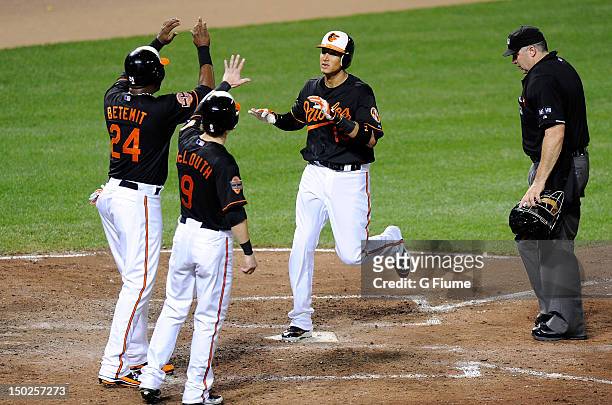 Manny Machado of the Baltimore Orioles celebrates with Wilson Betemit and Nate McLouth after hitting a home run in the sixth inning against the...