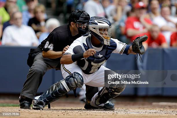 Martin Maldonado of the Milwaukee Brewers gets ready behind the plate as home plate umpire Angel Campos looks over his shoulder during the game...