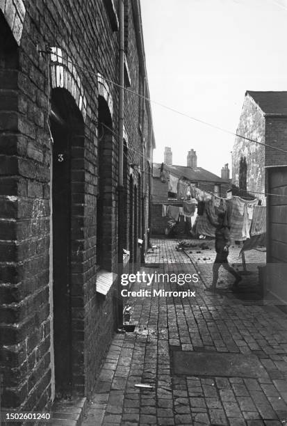 Exterior view of a Birmingham terraced house showing a woman hanging out her laundry. November 1971.