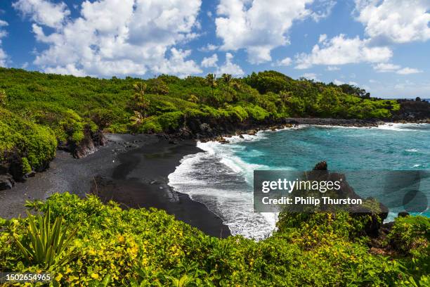 berühmter schwarzer sandstrand und atemberaubender blick auf die küste in maui an der straße nach hana an einem sonnigen tag - beach sand and water hawaii stock-fotos und bilder