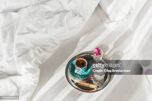 tray with coffee, sweets and water in bedroom. morning pleasure, breakfast in bed. - americano stockfoto's en -beelden