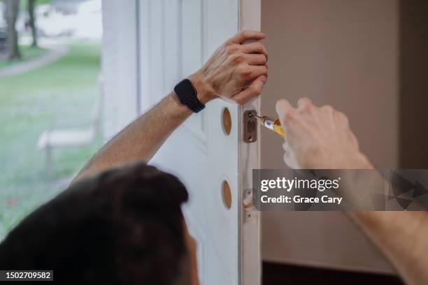 man replaces door hardware - cacciavite foto e immagini stock