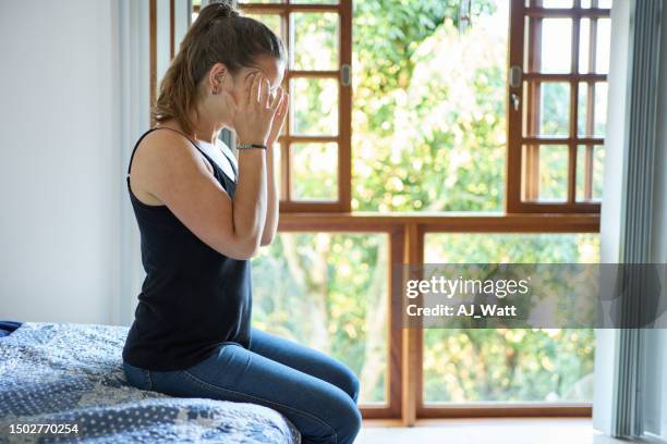 mujer sentada en la cama sufriendo de dolor de cabeza en casa - sien fotografías e imágenes de stock