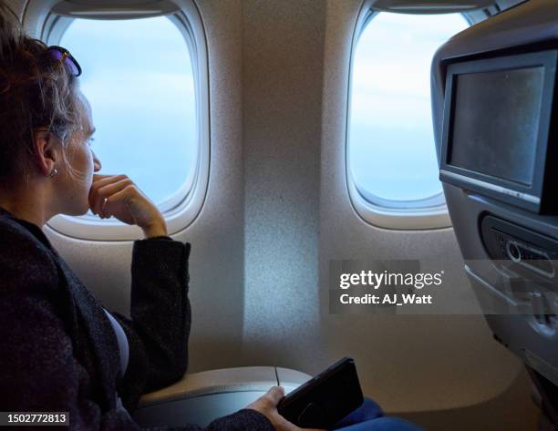 mujer viajera en el avión mirando por la ventana - airplane part fotografías e imágenes de stock