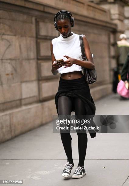 Model is seen wearing a white crop top, black spandex and Converse sneakers outside the Marc Jacobs show on June 26, 2023 in New York City.