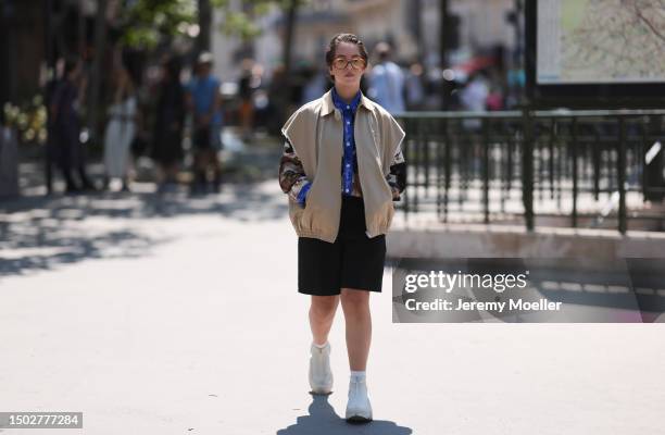 Fashion Week Guest is seen wearing brown transparent shades, a blue and brown shirt from Kid Super Studios which is white buttoned, a beige Miu Miu...