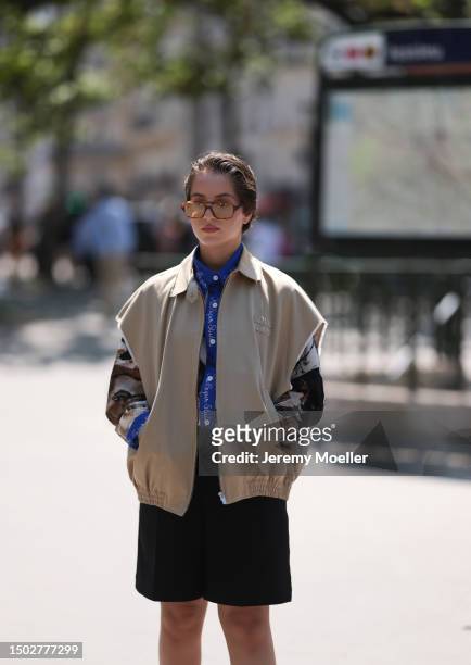 Fashion Week Guest is seen wearing brown transparent shades, a blue and brown shirt from Kid Super Studios which is white buttoned, a beige Miu Miu...