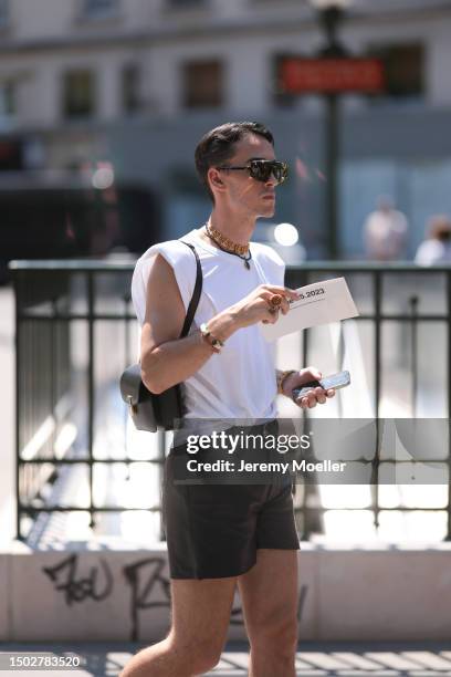 Fashion Week Guest is seen wearing black and brown sunglasses, lots of gold jewelry, a shite sleeveless top, a black bag, black belt and dark green...