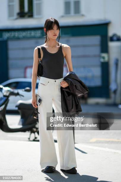 Guest wears a black tank-top, white latte matte denim wide legs pants, a black shiny leather jacket, a black shoulder bag, black sneakers , outside...