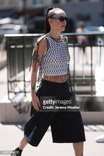 Fashion Week Guest is seen wearing miu miu shades, a belly-free tank top under a black web containing of many black pearls, a black bag, a dark...
