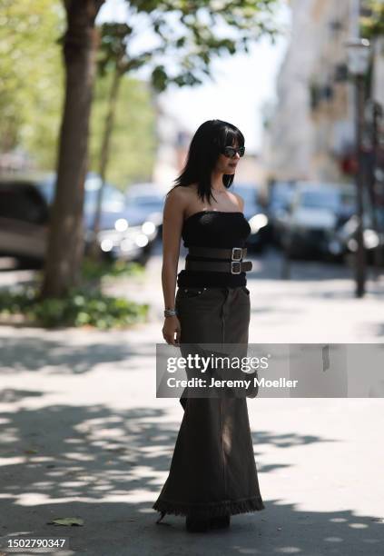 Maria Bernad is seen wearing a strapless top held by two big brown belts, a mugler bag with silver ornaments, a beown jeans skirt and black plateau...