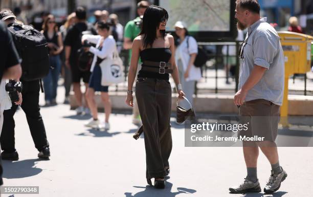 Maria Bernad is seen wearing a strapless top held by two big brown belts, a mugler bag with silver ornaments, a beown jeans skirt and black plateau...