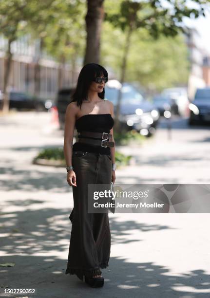 Maria Bernad is seen wearing a strapless top held by two big brown belts, a mugler bag with silver ornaments, a beown jeans skirt and black plateau...