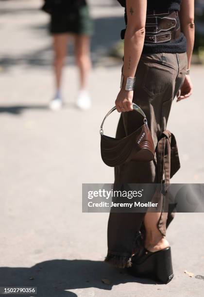 Maria Bernad is seen wearing a strapless top held by two big brown belts, a mugler bag with silver ornaments, a beown jeans skirt and black plateau...