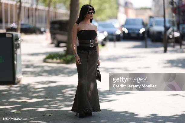 Maria Bernad is seen wearing a strapless top held by two big brown belts, a mugler bag with silver ornaments, a beown jeans skirt and black plateau...