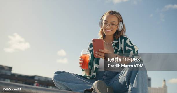 young girl, headphones and cellphone in city with cool drink, mobile texting and social media app on mockup sky. happy gen z woman, urban influencer and listening to music with smartphone outdoor - gen i stock pictures, royalty-free photos & images