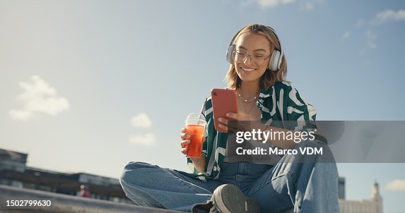 Young girl, headphones and cellphone in city with cool drink, mobile texting and social media app on mockup sky. Happy gen z woman, urban influencer and listening to music with smartphone outdoor Young girl, headphones and cellphone in city with cool drink, mobile texting and social media app on mockup sky. Happy gen z woman, urban influencer and listening to music with smartphone outdoor