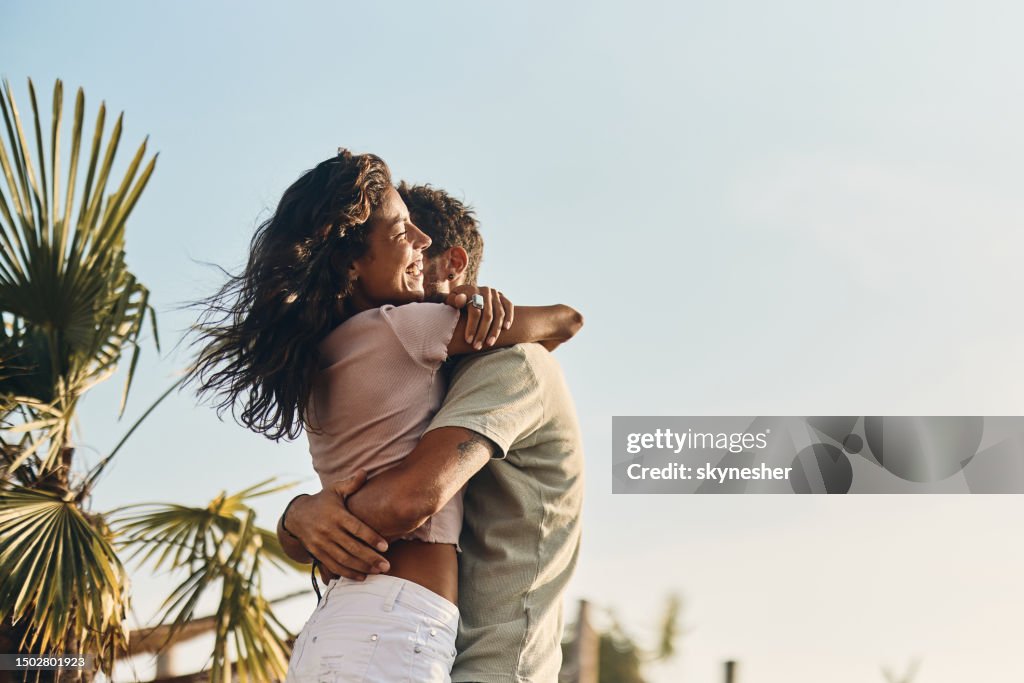 Young carefree couple embracing in summer day on the beach.
