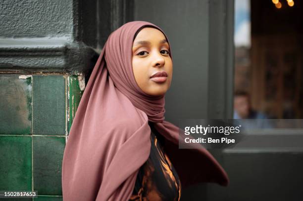 portrait of young woman in hijab leaning against building - adult portrait stock pictures, royalty-free photos & images