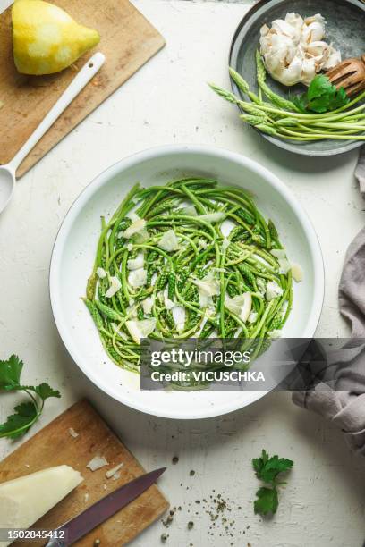 delicious wild asparagus salad with nuts and cheese on kitchen table with ingredients and utensils, top view. - parmesan stock-fotos und bilder
