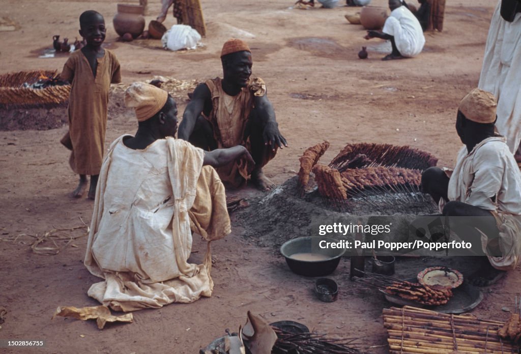 Traders Gather Round To Cook Grilled Meat On Skewers Known As Suya traders-gather-round-to-cook-grilled-meat-on-skewers-known-as-suya