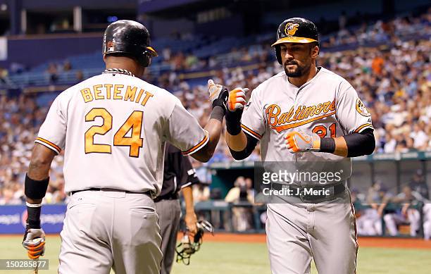 Outfielder Nick Markakis of the Baltimore Orioles is congratulated by Wilson Betemit after scoring against the Tampa Bay Rays during the game at...