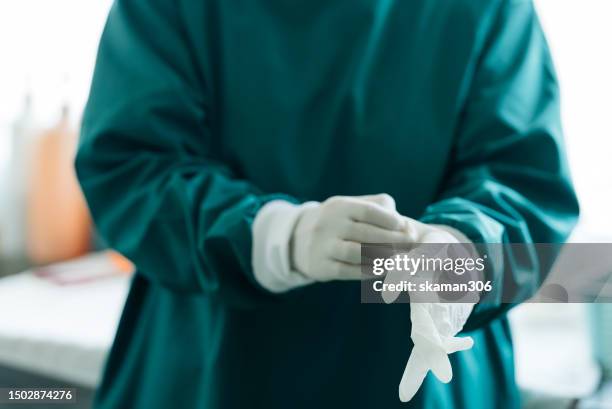 motivated doctor and surgeon dressing up for a challenging patient case in the operation room - doctor scrubs stock pictures, royalty-free photos & images