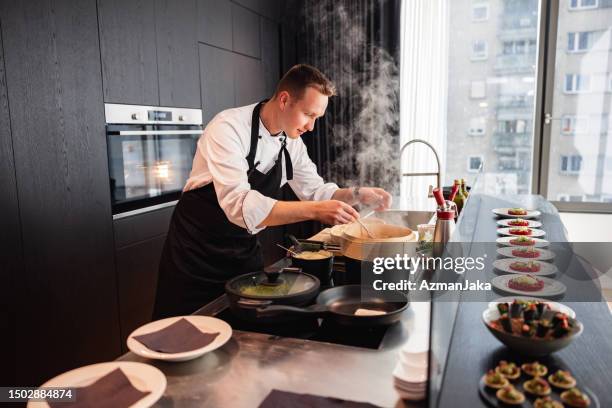 atractivo chef privado para adultos jóvenes cocinando en un apartamento elegante - uniforme de chef fotografías e imágenes de stock