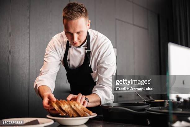 blonder kaukasischer männlicher privatkoch, der gerichte für eine dinnerparty in einer schicken wohnung anrichtet - food plating stock-fotos und bilder