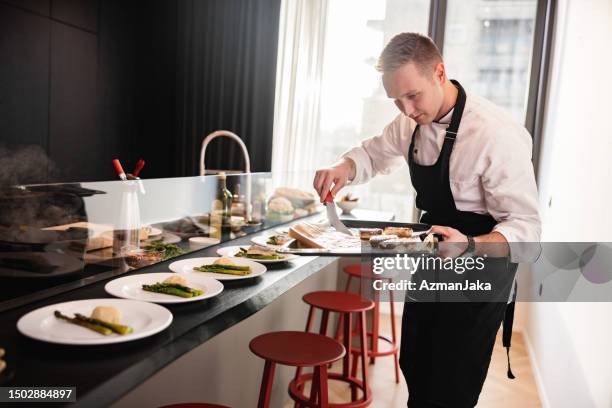 a young blonde chef plating the food before a fancy bachelorette party in a modern apartment - home chef stock pictures, royalty-free photos & images