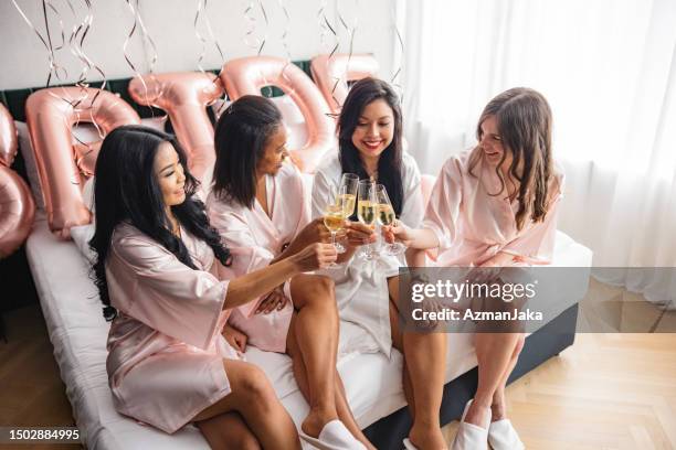multiracial group of female friends toasting while getting ready for a bachelorette party - bachelorette stock pictures, royalty-free photos & images