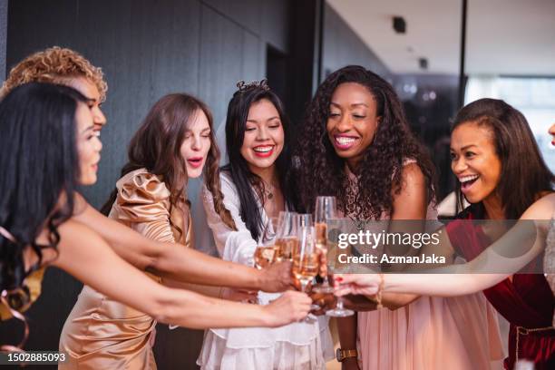 eine vielfältige gruppe von freundinnen, die während eines junggesellenabschieds auf die zukünftige braut anstoßen - junggesellinnenabschied stock-fotos und bilder
