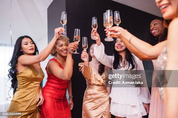 happy group of multiracial female friends raising glasses at a bachelorette party - bachelorette stock pictures, royalty-free photos & images