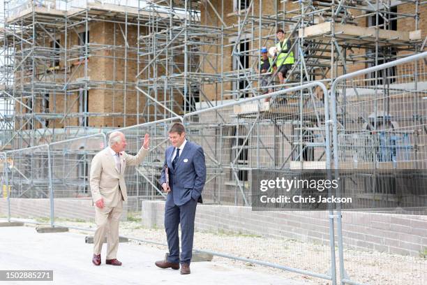 King Charles III greets workers as he visits a Poundbury construction site with Peter Lacey, Poundbury Project Manager, on June 27, 2023 in...