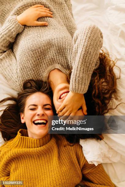 two young women lying on back and laughing together - lying on back girl on the sofa stock pictures, royalty-free photos & images