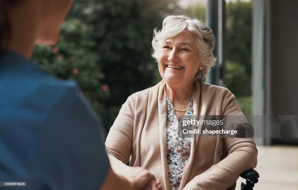 Händchenhaltende, Krankenschwester und glückliche Seniorin im Rollstuhl mit Hilfe oder Unterstützung für das Wohlbefinden. Ältere geduldige Person mit einer Behinderung und Pflegekraft, die über Gesundheitsversorgung, Lächeln oder medizinische Verso