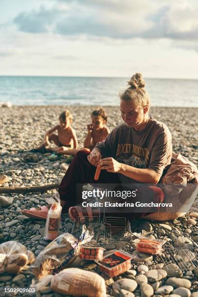 a tourist cooks sausages on a campfire - boy warming up stock pictures, royalty-free photos & images