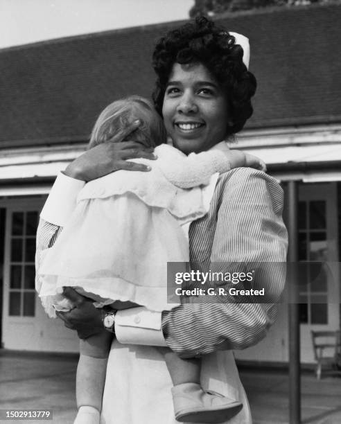 Bermudian student nurse Helen Sherlock in uniform and holding young patient Susan Brown at Botleys Park Hospital in Chertsey, Surrey, England, 15th...